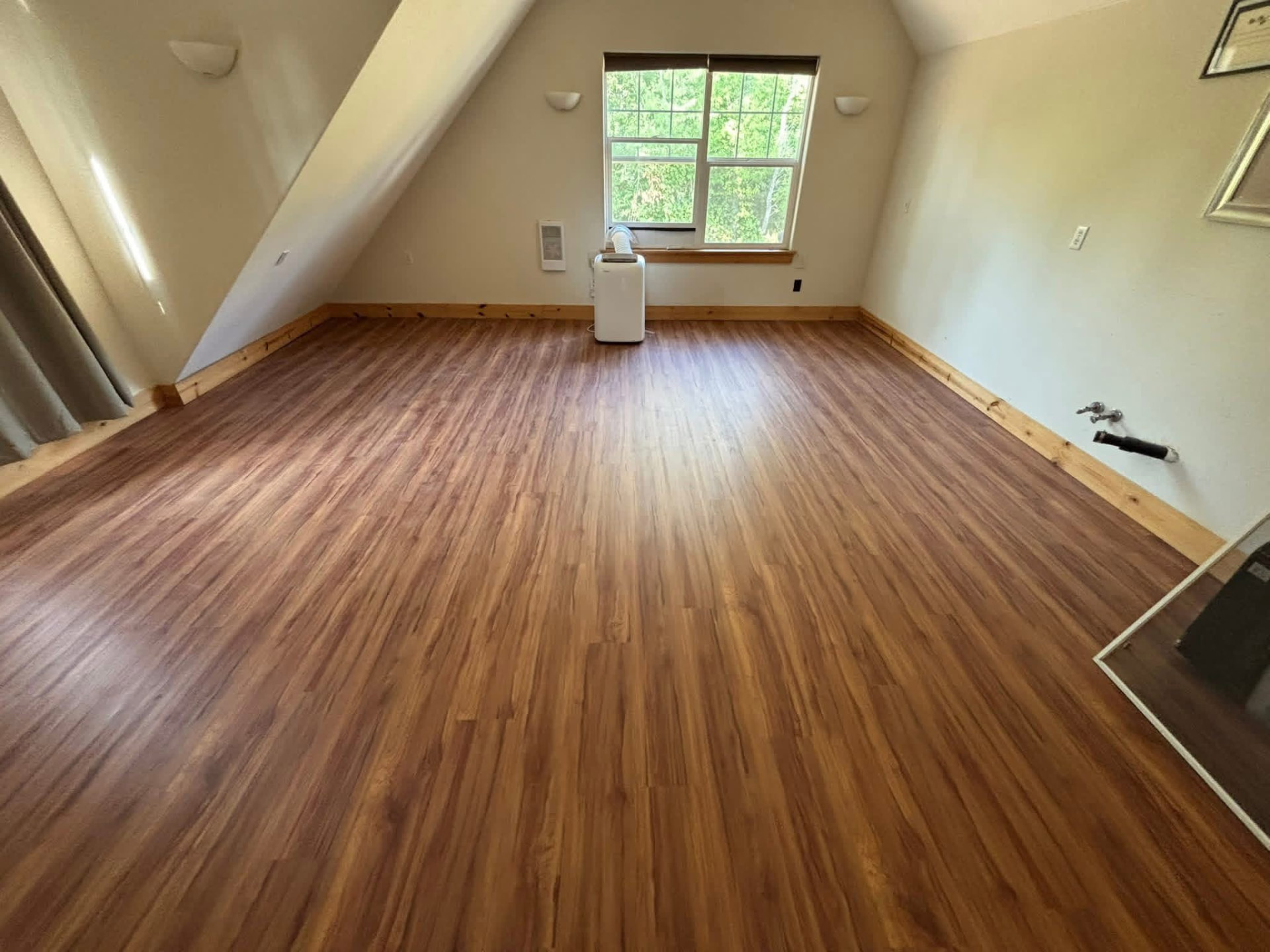 Upstairs bonus room with vaulted ceiling, warm plank flooring and new pine base trim
