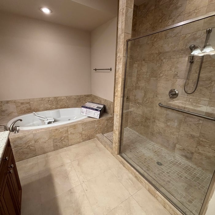 Bathroom with travertine tile, corner jetted tub and a large glass walk-in shower