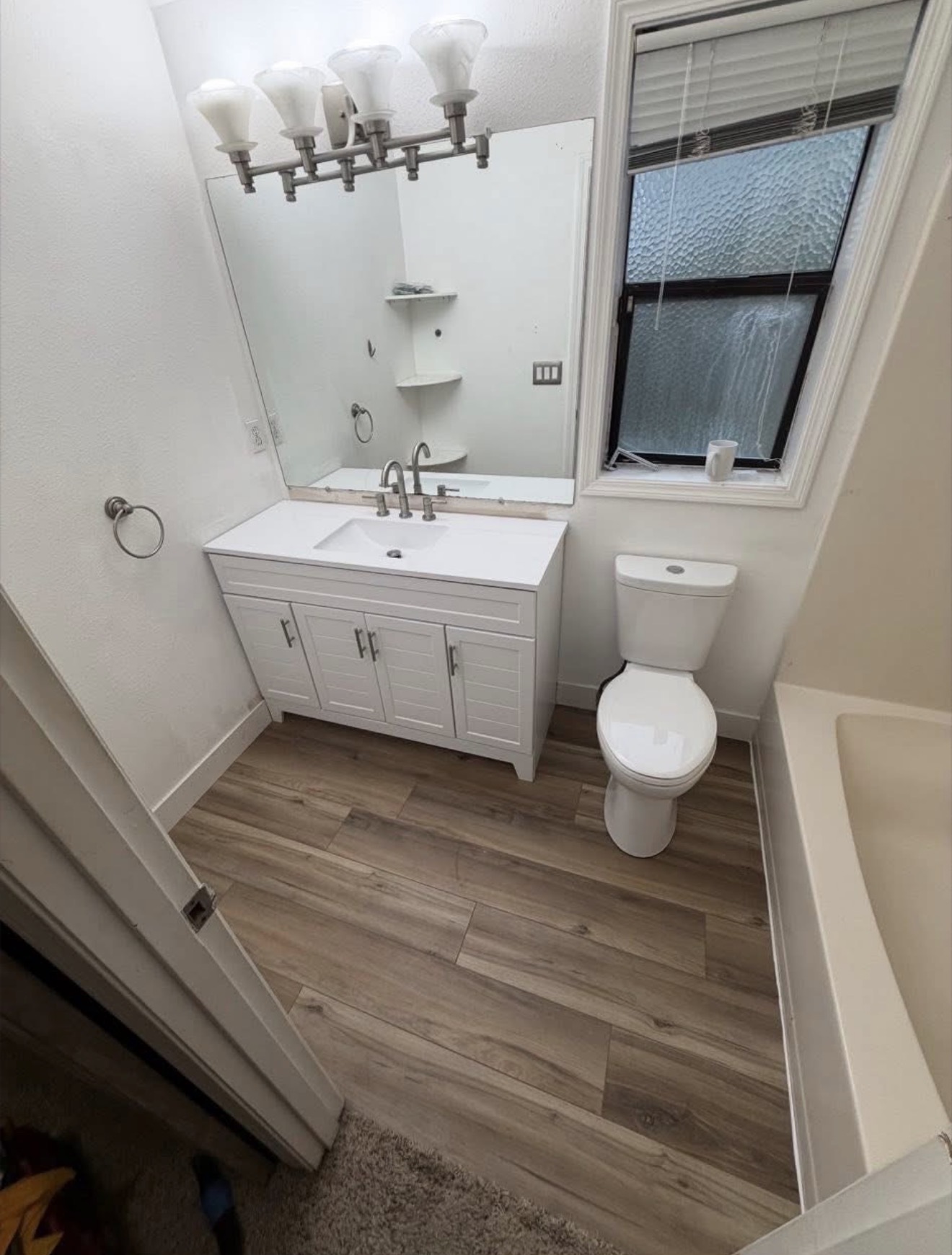 Guest bathroom with white shaker vanity, quartz top and wood-look vinyl plank flooring