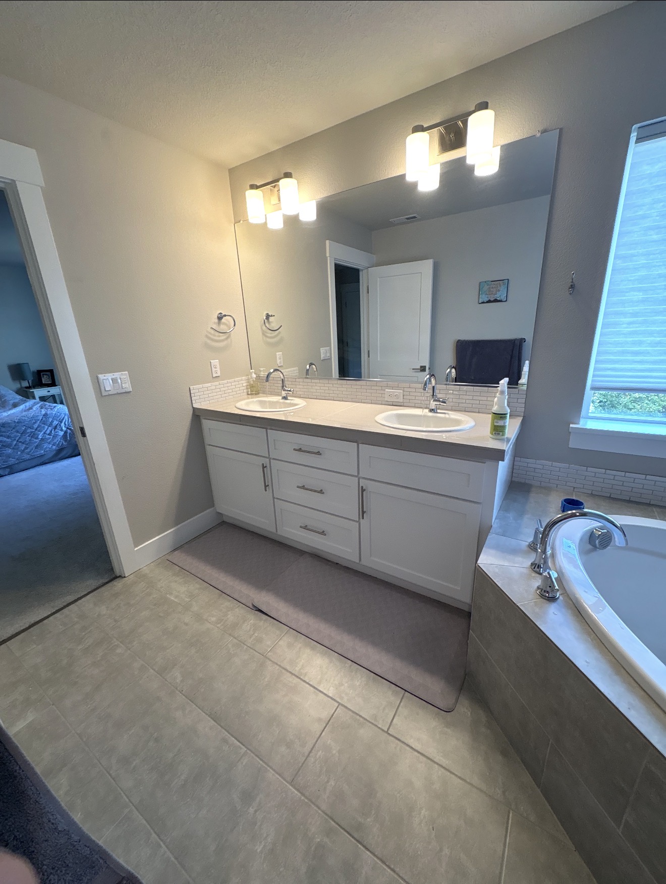 Bathroom with white double vanity, subway tile backsplash and a tiled corner soaking tub