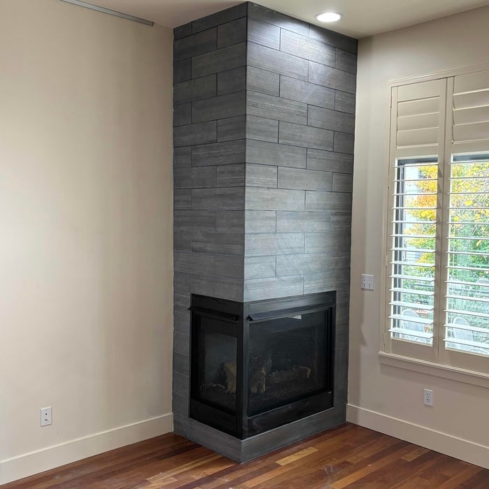 Finished charcoal large-format tile fireplace surround running floor to ceiling