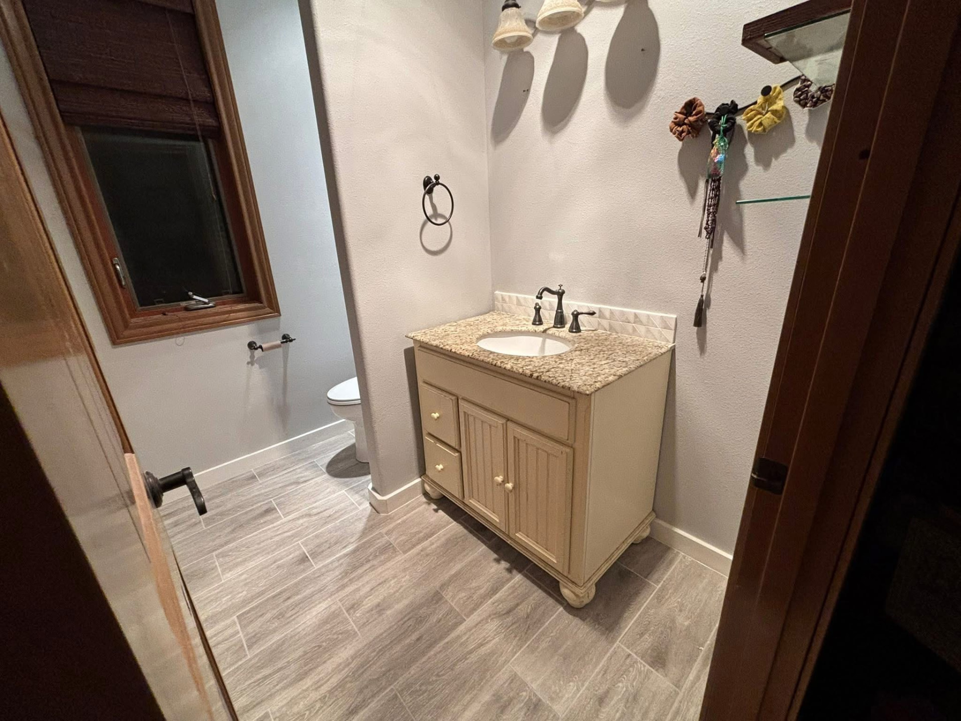 Guest bathroom with a cream vanity, granite top and wood-look plank tile flooring